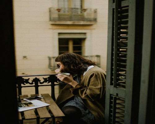 A person taking a break, holding a cup of coffee near a window