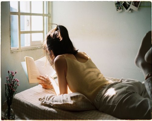 Person reading a book by the window with soft daylight
